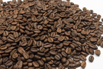 Heap of coffee beans sprinkled on a white background