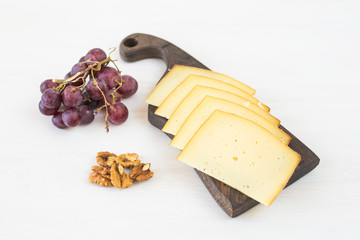 Fresh products. Sliced cheese with grapes and nuts on rustic table.