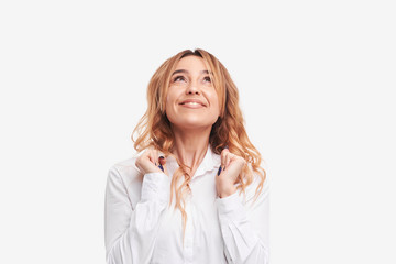 Portrait of wishful young redhead woman in casual white clothes, crossing her fingers, biting her lower lip, feeling nervous before important event. Body language. Fun emotions