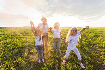 Fototapeta premium Przyjaźń, święta indyjskie i koncepcja ludzie - młode kobiety i dzieci tańczą na polu latem na festiwalu holi