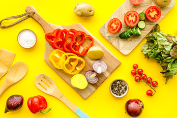 Fototapeta na wymiar Vegan food cooking with raw vegetables on yellow background top view