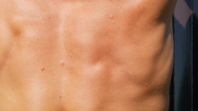 The back muscles of a young tanned sex worker who works with tools. Young body
