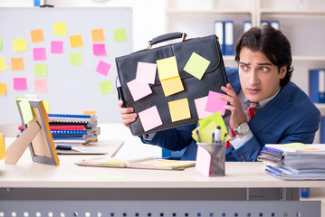 Young male handsome employee in conflicting priorities concept 
