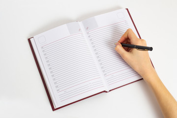 Hand with pen is ready to write in an open notebook