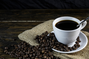 Cup of coffee and coffeCup of coffee and coffee beans on a rough wooden background.e beans on a rough wooden background.
