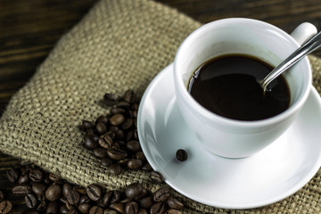 Cup of coffee and coffee beans on a rough wooden background.