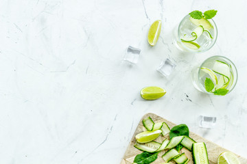 fresh drink with lime, cucumber and ice on white background top view mock up