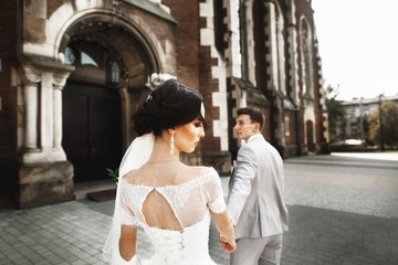 Beautiful newlywed couple walk near old christian church