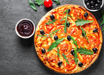 Pizza with Mozzarella cheese, Tomatoes, pepper, olive, Spices and Fresh arugula. Italian pizza. Pizza Margherita or Margarita on Dark grey black slate background