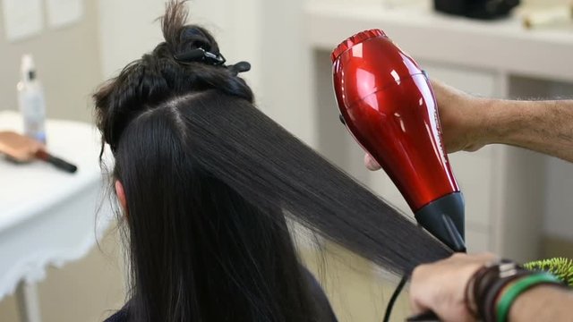 Slow hair drying of long black hair by professional hairdresser 