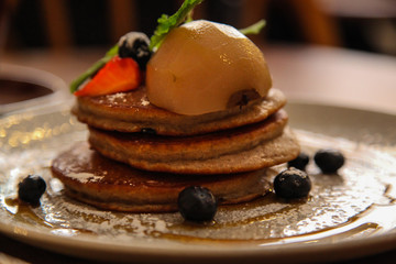 Stack of buckwheat pancakes topped with a poached pear