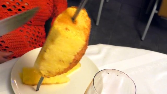 cinnamon pineapple cut in slices with a sword in a Brazilian churrascaria restaurant.