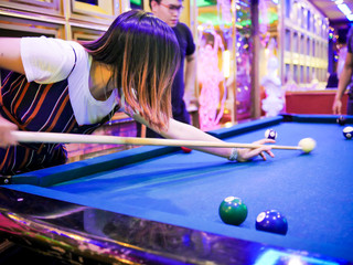 Young man play billiards in the colorful club - Aiming white ball to shot