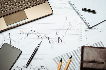 Analysis of financial charts on paper, notebook and pen