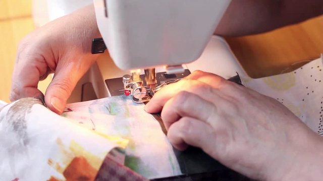 Close-up shot . Woman's hands is stitching by sewing machine part of patchwork quilt.