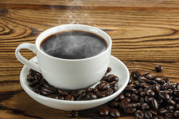 Hot coffee with hot steam and coffee beans on wooden table
