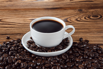 Hot coffee with hot steam and coffee beans on wooden table