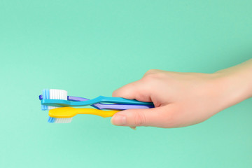 The woman holds toothbrushes in her hand on a green background.