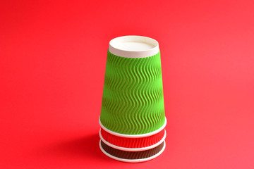 Red, green, brown paper cups on a red background. Copy space.