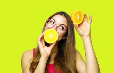 Portrait of funny happy girl holding halves of orange near face