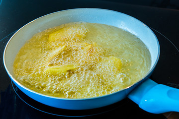 French fries in blue and white pan with boiling oil