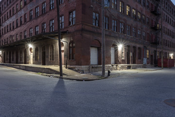 Corner of a large red brick vintage multiple story warehouse with lights