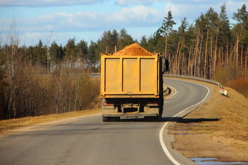 Transportation of building materials, heavy overloaded truck dump truck carries sand on a country road © Ilya