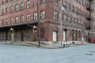 Fototapeta na wymiar On the corner of a vintage multiple story red brick industrial warehouse in a depressed urban area