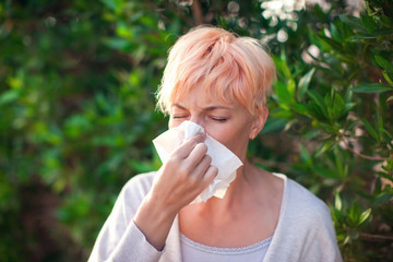 Young woman with short hair sneezing into tissue. flu, allergy, runny nose. Healthcare concept