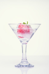 Frozen splashes of clean, spring water, in a glass with frozen strawberries, on a white background.
