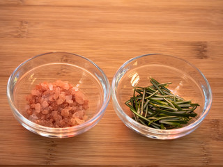 Crystal bowls with himalayan pink salt and rosemary on a wooden table