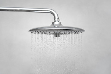 Water running from shower head and faucet in modern bathroom. Rain Shower turned, ceiling shower head closeup in the shower stall.