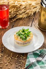 Traditional Russian salad Mimosa with parsley on top on wooden table