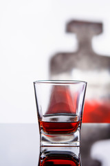 glass of whiskey or cognac with bottle on glass surface