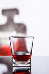 glass of whiskey or cognac with bottle on glass surface