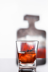 glass of whiskey or cognac with bottle on glass surface