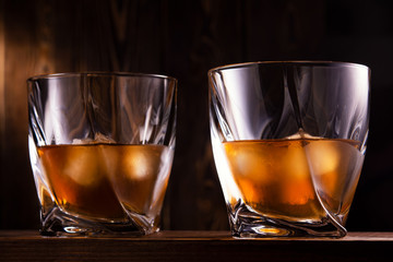 two glasses of whiskey over wooden background