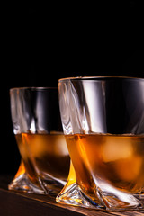 two glasses of whiskey or cognac over wooden background