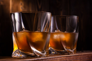two glasses of whiskey or cognac over wooden background