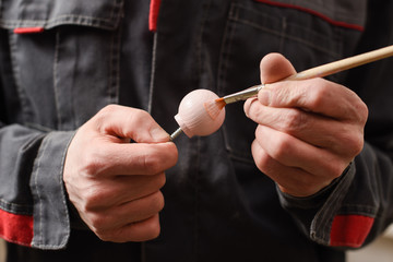 Carpenter at work. Close up of painting pink wooden detail with brush