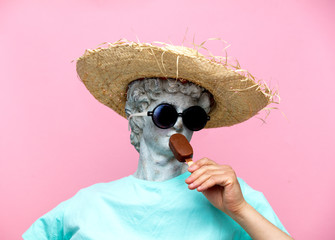 Antique bust of male in hat with ice-cream on pink background.