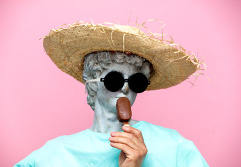 Antique bust of male in hat with ice-cream on pink background.