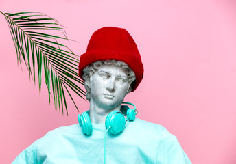 Antique bust of male in hat with headphones on pink background.