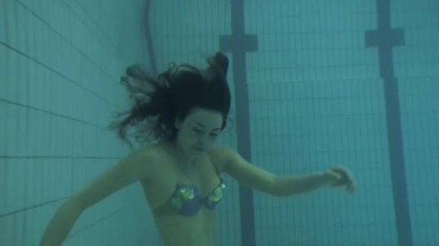Mermaid underwater model in swimming pool. Young woman freediver swims in undine water nymph costume with monofiin.