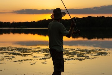 angler catching the fish during sunset