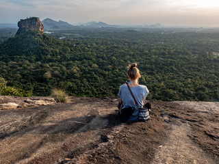 Young caucasian woman sitting on the top of the Rock Pidurangala. Sri Lanka, March 10, 2019.