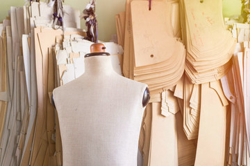 Mannequin in bespoke tailor studio against cardboard sewing patterns.