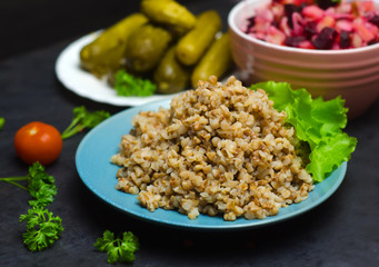 Russian buckwheat porridge near greens selective focus on wooden background