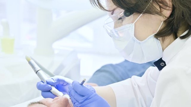 Close-up of a woman dentist examining the oral cavity of a male patient at the age. High key professional work of a dentist in the dental clinic