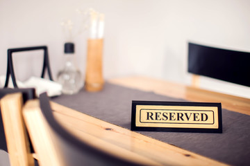 Reserved sign with capital letters on dining table in restaurant
